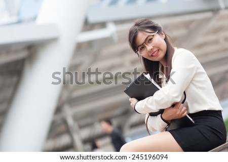 Smile asian businesswoman hold paper and document file.Happy and smile sitting on sidewalk.