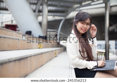 Happy and relax businesswoman.asian businesswoman smile and sitting on sidewalk.wear glasses.