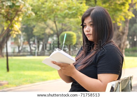 Woman sitting in a park thinking what to write in books.