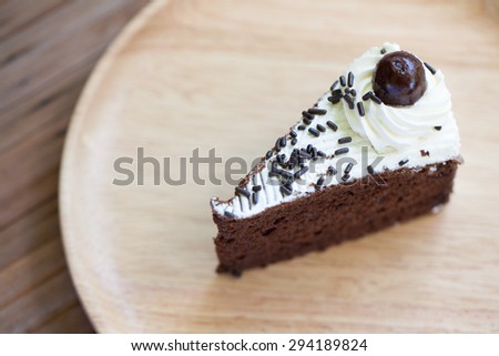 Chocolate cake, put it on a plate placed on a wooden table made from wood as well.