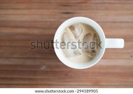 Glass of cold coffee on a wooden table. Coffee mixed with milk