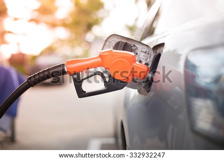 Gas pump nozzle in the fuel tank of a bronze car, refuel