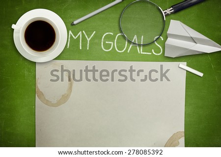 My goals concept on green full frame blank blackboard with coffee cup. empty paper and magnifying glass