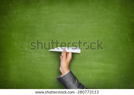 Businessman hand holding paper plane on front of vintage full frame black green blackboard no frame