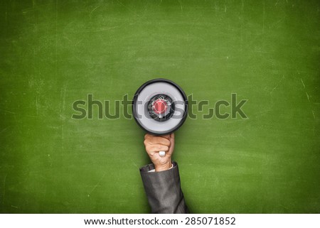 Businessman hand holding megaphone on front of vintage full frame green blank blackboard no frame