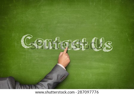 Contact us concept on green blackboard with businessman hand pointing