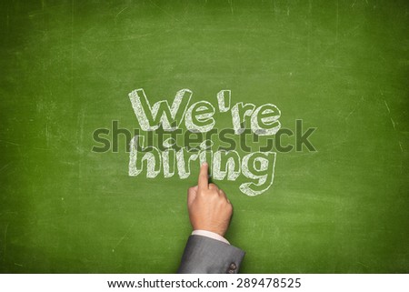 We are hiring concept on green blackboard with businessman hand