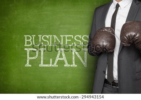 Business plan on blackboard with businessman on side wearing boxing gloves