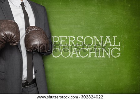 Personal coaching on blackboard with businessman wearing boxing gloves