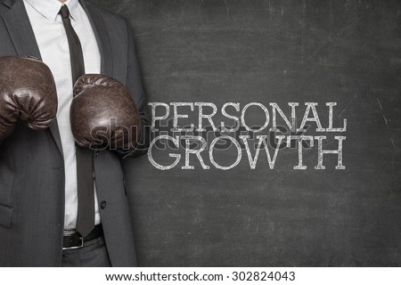 Personal growth on blackboard with businessman wearing boxing gloves