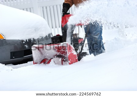 homeowner clearing snow from driveway with snow blower