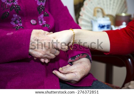 The grand mother hold the hand of the grand daughter after giving her the bracelets.