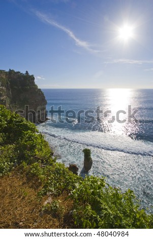 Bright sun over a clear blue sea by the cliff