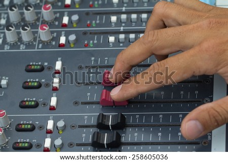 An expert adjusting audio mixing console.select focus