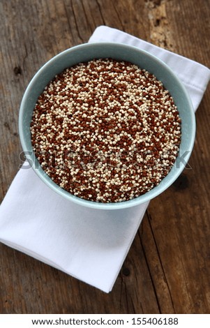 Quinoa Red And White Grain Uncooked In A Blue Bowl On A Wooden Table Top. Quinoa Is A Food Substitute For Wheat Grains As It Is Gluten Free And A Great Source Of Protein For Those On A Vegetarian Diet