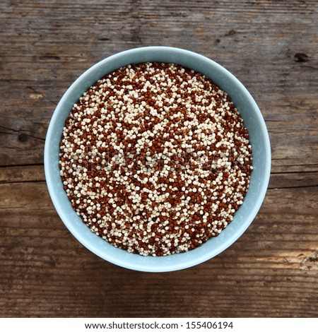 Quinoa Red And White Grain Uncooked In A Blue Bowl On A Wooden Table Top. Quinoa Is A Food Substitute For Wheat Grains As It Is Gluten Free And A Great Source Of Protein For Those On A Vegetarian Diet