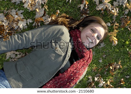 Young Woman Lying On The Grass With Autumn Leaves On The Ground