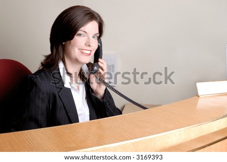 Attractive Brunette Young Woman Answering The Phone At A Company Reception Desk