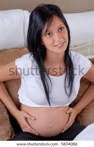 stock photo Pregnant Teen Girl Feeling Her Baby Kicking As She Lies In Bed