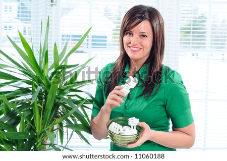 Pretty Young Woman Changing The Light Bulbs In Her Home To Low Energy Compact Fluorescent CFL