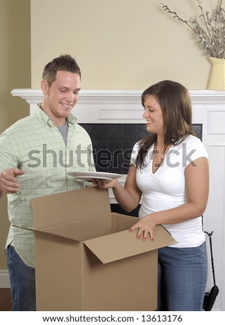 Attractive Young Couple Unpacking Dishes In Their New Home