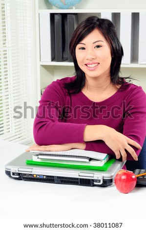 Happy Asian Student In Class Leaning On Her Books And Computer