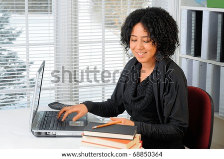Young Woman Sat At Her Desk Using A Laptop Computer