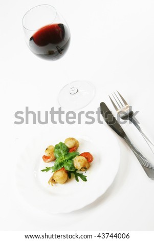 Delicious sea food (scallops) decorated with basil and rucola with a glass of red wine