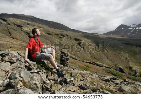 Young male traveller, photographer resting and enjoying the beautiful view of mountains in Iceland