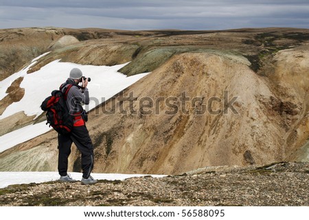 Young male traveller, photographer taking photos of the beautiful view of mountains in Landmannalaugar region ofIceland