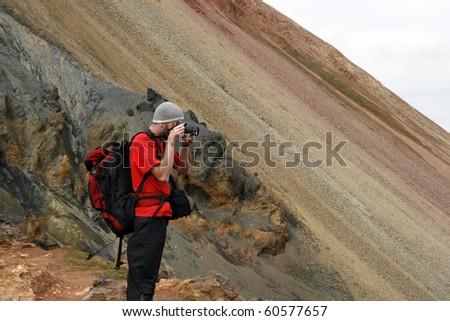 Young male traveller, photographer taking photos of the beautiful view of mountains in Iceland