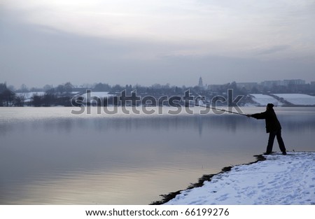 Beautiful winter landscape - man fishing during sunset