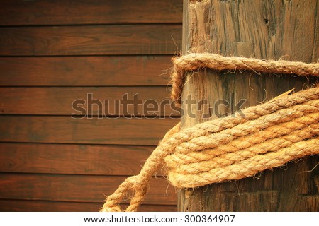 Rope wrapped around wooden post in old wooden wall