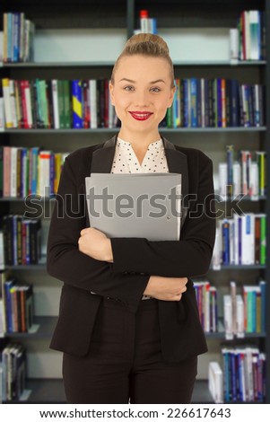 woman in a jacket with a folder in hands in a library