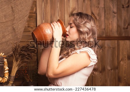 young woman drinking milk on a background of the rural interior