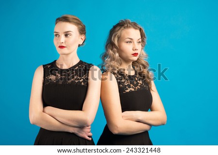 Two women in identical dresses are angry at each other/Two women in identical black dresses are angry at each other