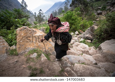 TUPE, LIMA, PERU - FEBRUARY 3: Portrait of a old woman in  traditional clothing, while climbing the hill on February 03, 2010 in Tupe, Peru. In the Andes, people walk a lot on difficult  trails.