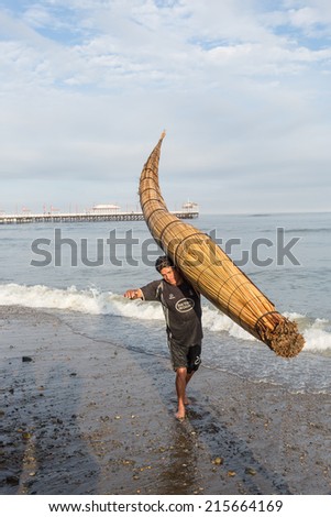 HUANCHACO, PERU - CIRCA 2014: A fisherman enters the sea with his cattail canoe circa 2014 in Huanchaco, Peru. Reed canoes are traditional craft from the Inca era