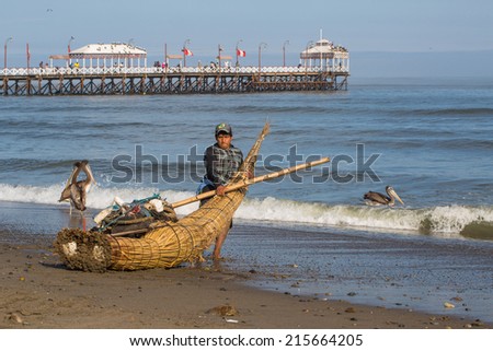 HUANCHACO, PERU - CIRCA 2014: A fisherman enters the sea with his cattail canoe circa 2014 in Huanchaco, Peru. Reed canoes are traditional craft from the Inca era