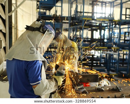 Worker grinding steel in work shop for maintenance in factory
