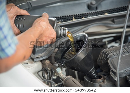 Mechanic draining engine oil from a car for an oil change at an auto shop