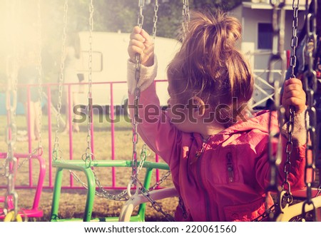 toned portrait of Sad little girl sitting on swing in a park, looks for her mum