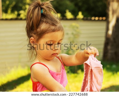 Little girl play and changes clothes at summer day