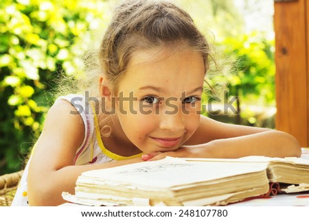 cute curly school girl reading an old book outside