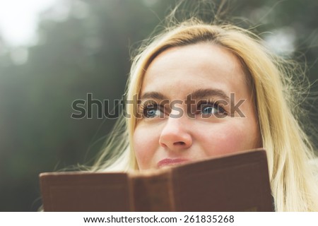 Toned portrait of Happy blonde woman reading book outdoors