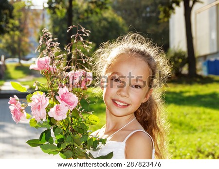 Cute little Girl hold roses and smile at summer day