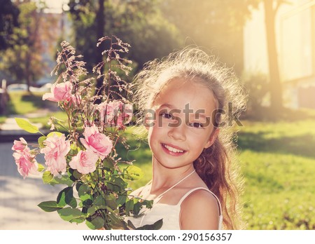 Toned portrait of Cute little Girl hold roses and smile at summer day