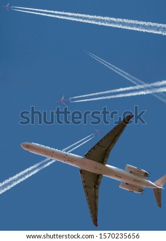 Jumbo jet and airplanes flying across blue sky