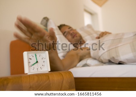 Man hitting snooze on his alarm