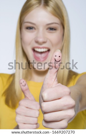 Young woman with happy face drawn on thumbs